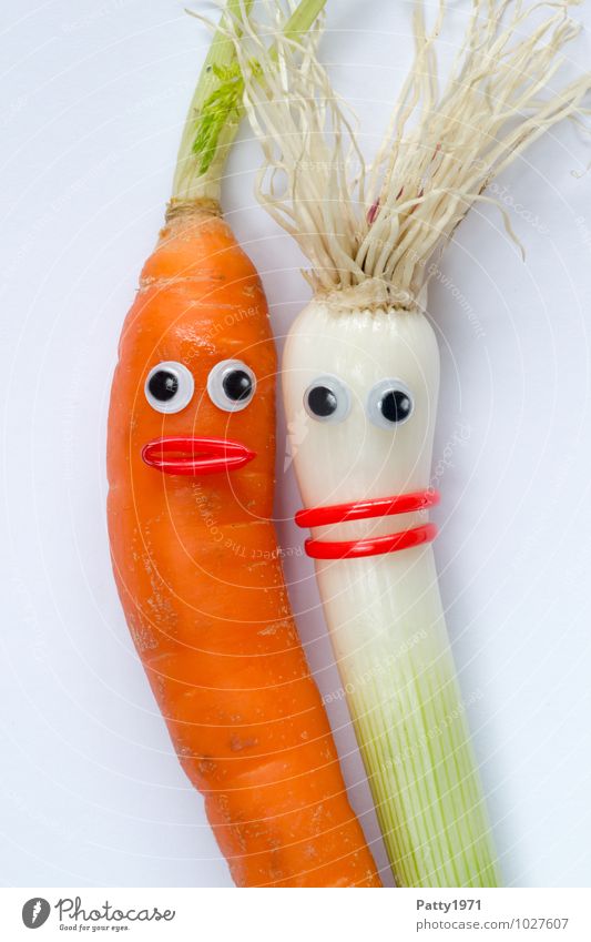 Vegetables with googly eyes glued on them depict a couple in love. Carrot Onion Shallot Face Eyes Mouth Green Orange White Happiness Acceptance Agreed Sympathy
