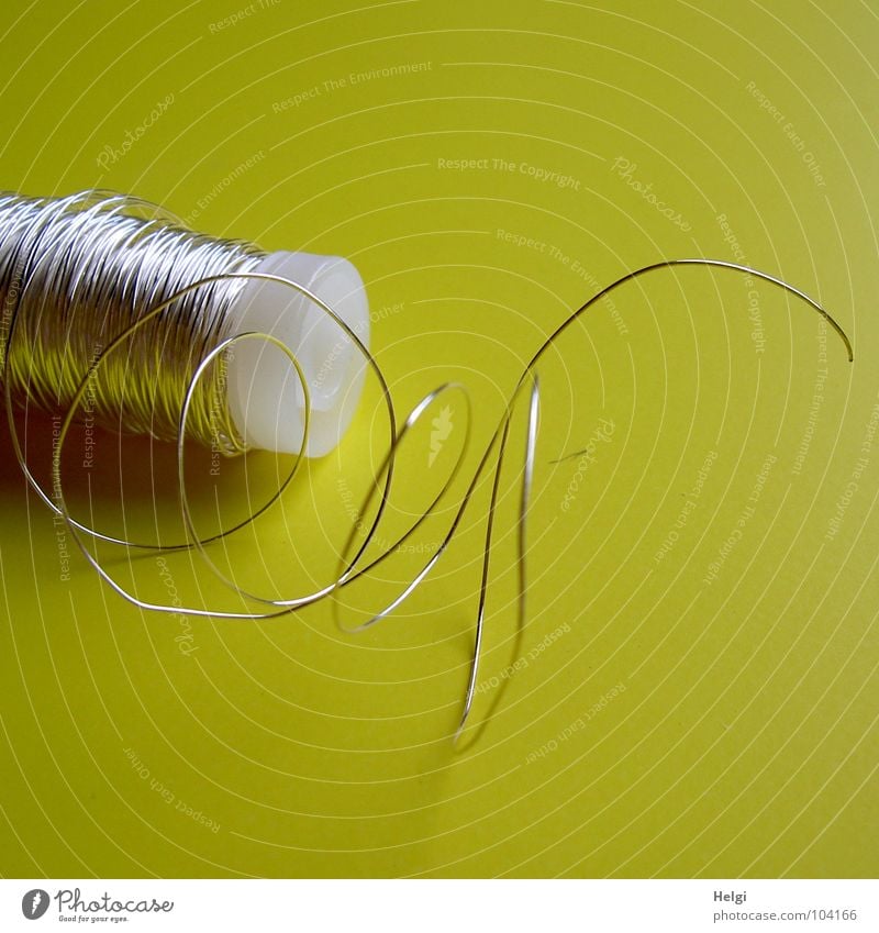 Roll with thin silver wire in front of yellow background Wire Coil Rolled up Thin Long Delicate Handicraft Jewellery Embellish Bind fast Arrange Bond Yellow