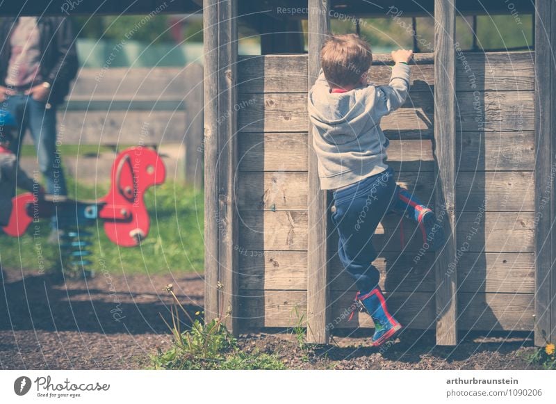 Child with coloured rubber eifel climbs on wooden house at playground Leisure and hobbies Playing Garden play tower Kindergarten Human being Masculine Man