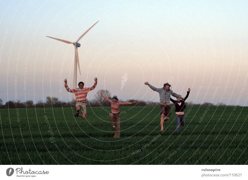 Jump! Green Field Human being Motionless Rotate White Large Thin Technical Meadow Juicy Evening sun Red Engagement Joy Wind Wind energy plant Energy industry