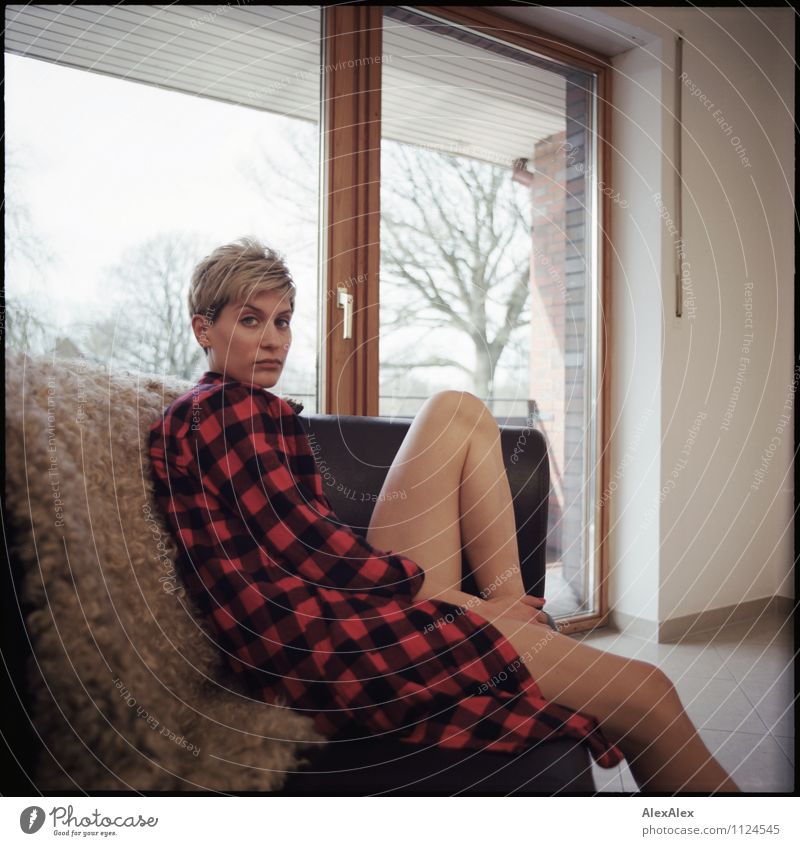 young athletic woman with plaid shirt and bare legs sits on a sofa with sheepskin Flat (apartment) Sofa Room French windows Sheepskin Young woman
