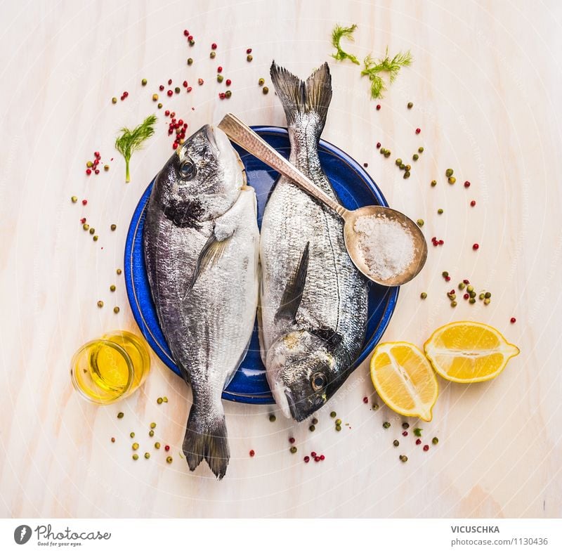 Two Dorado fish on blue plate with oil and lemon Banquet Style Design Healthy Eating Table Kitchen Gourmet delicious Fish Raw Ingredients Herbs and spices