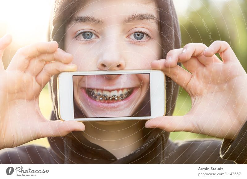 Teen holds cell phone in front of mouth with picture of his mouth Lifestyle Style Design Joy Show your teeth Telecommunications Cellphone PDA Technology