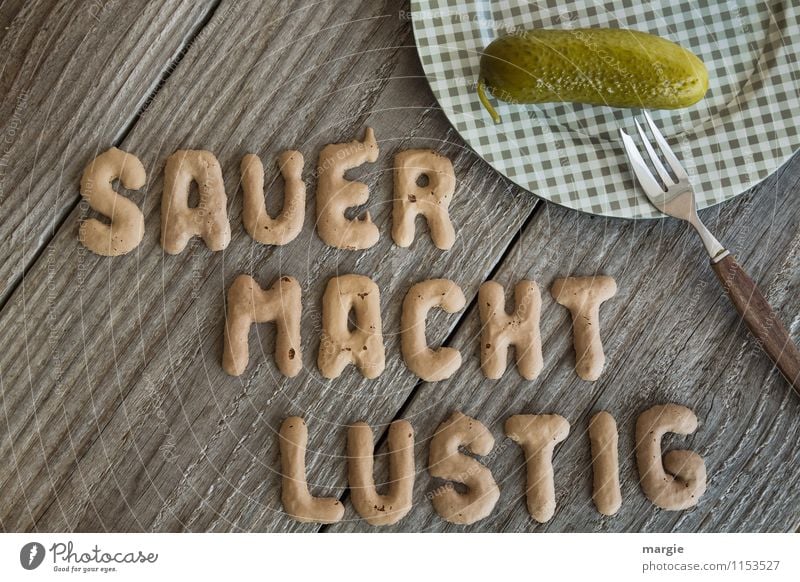 The letters SAUER MACHT LUSTIG next to a plate with a pickled cucumber and a fork Food Vegetable Cucumber Nutrition Breakfast Dinner Buffet Brunch Picnic