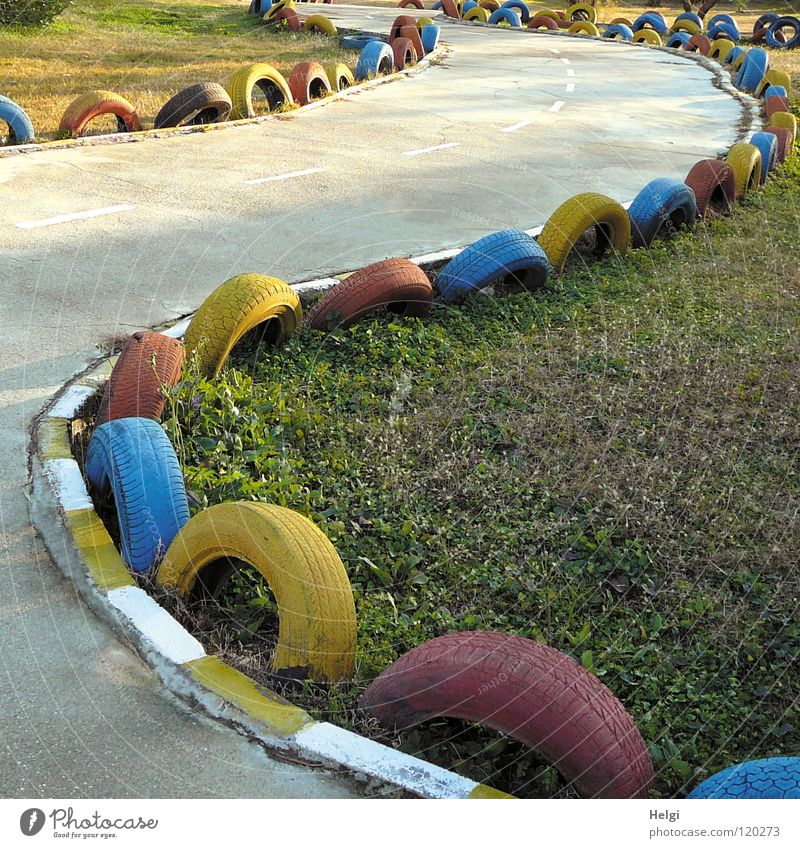 colourful tyres as protection on a curvy kart track and a meadow Car race Formula 1 Racecourse Speed Driving Concrete Corner Silhouette Border Dangerous Meadow