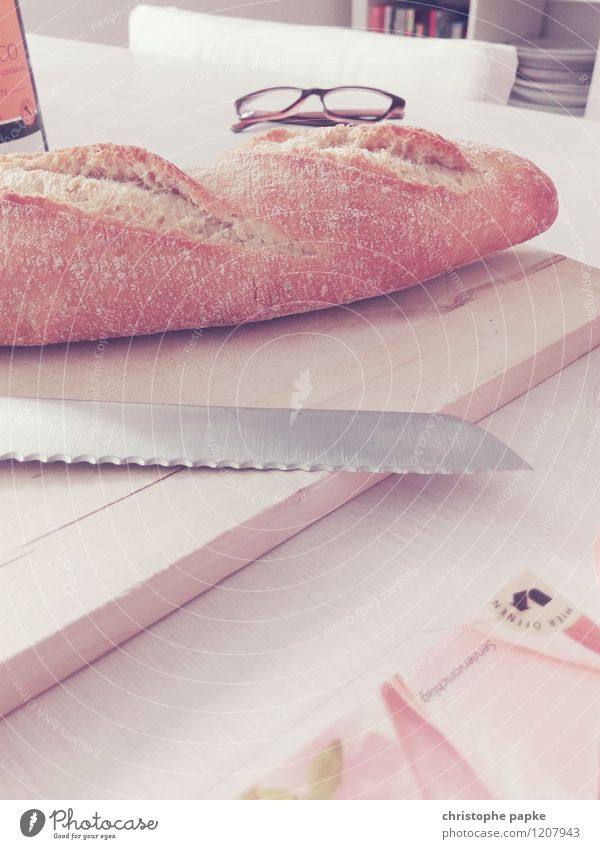 Baguette with knife on board on table Food Bread Nutrition Breakfast Knives Living or residing bread knife Eyeglasses Wooden board Table Colour photo