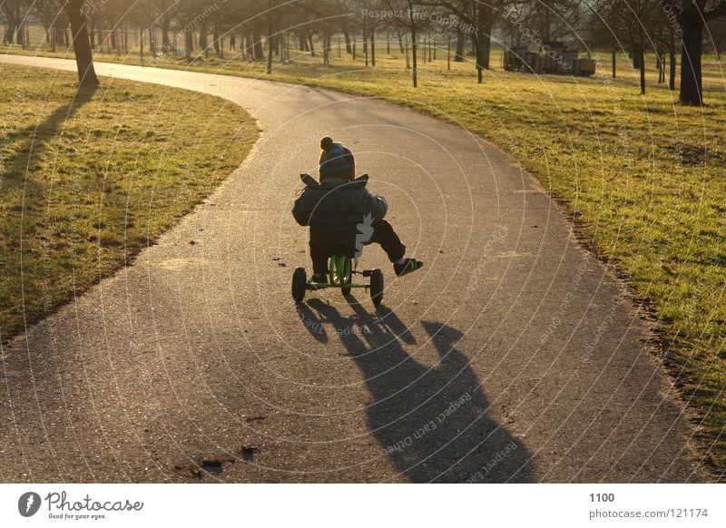 towards the sun Tricycle Driver Child Evening sun Sunset Vehicle Means of transport Footwear Musculature Boy (child) Street Lanes & trails tree meadow