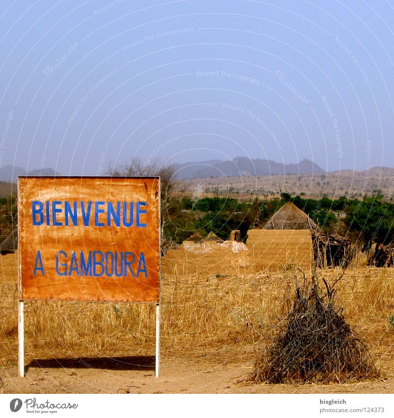 Welcome to Gamboura (Cameroon) Colour photo Exterior shot Deserted Copy Space top Mountain Africa Village Hut Signage Warning sign Poverty Brown Steppe