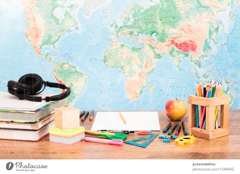 School accessories on desktop with map at background Fruit Apple Desk Study Workplace Tool Scissors Book Piece of paper Pen Disciplined colorful Crayon cube