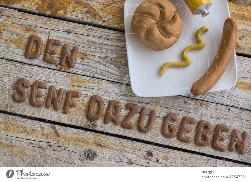 On a rustic wooden table, the letters DEN SENF DAZUgeben, a plate with sausage, bread rolls and mustard Food Meat Sausage Dough Baked goods Bread Roll
