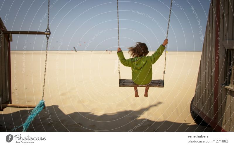 Child on a swing on a long sandy beach Swing Beach View from behind Blue sky North Sea Netherlands relaxation