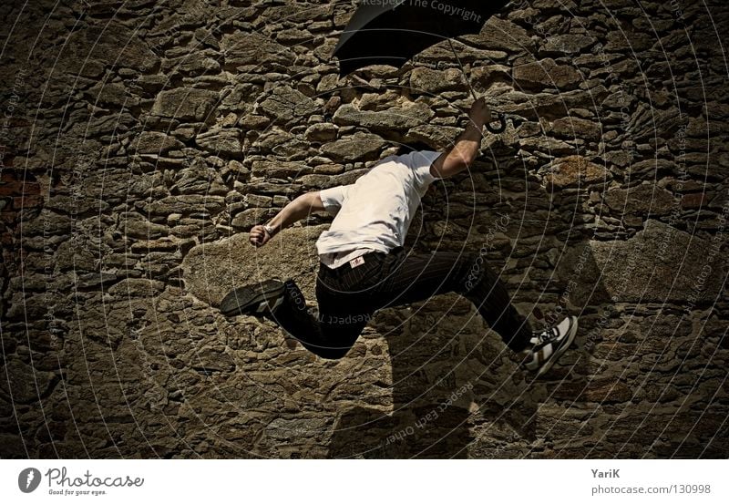 up and away Jump Umbrella Man T-shirt White Black Brown Stony Wall (building) Wall (barrier) Stone wall Plaster Drop shadow Happiness Cheerful