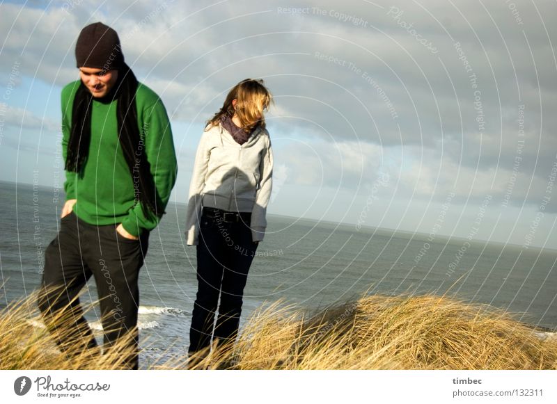 The two of us Man Woman Ocean Clouds Bad weather Beach Green Gray Sweater Scarf Cap Movement Going Grass Wind Divide Cold Hand Pants Dark Winter Human being