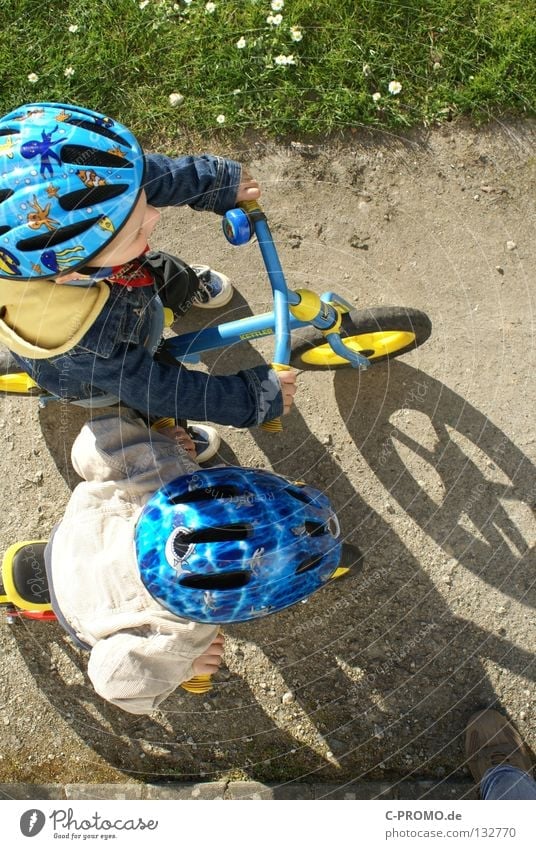 On your mark, get set, go... Child Helmet Safety Adversary Grass Meadow Bird's-eye view Playing Sporting event Competition Funsport Bicycle Shadow Beginning