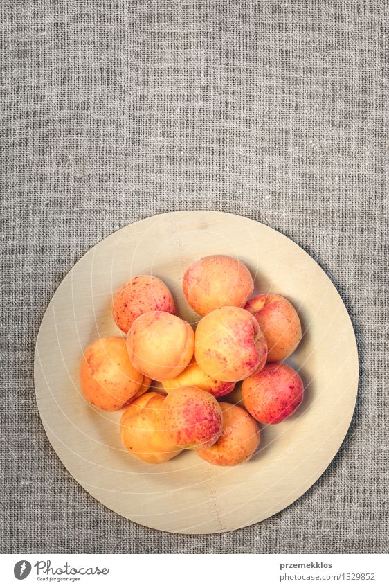 Fresh apricots straight from the garden on wooden plate Food Fruit Organic produce Plate Summer Nature Delicious Sweet Yellow Apricot healthy linen orange pit