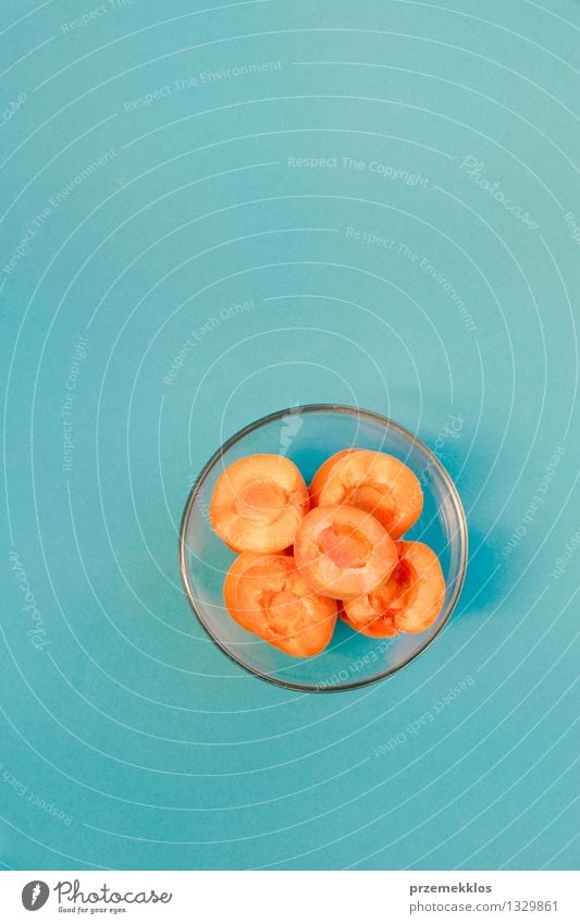 Sliced apricots in bowl on blue background Fruit Bowl Summer Nature Fresh Bright Blue Orange Apricot food glassware healthy Organic pit Plain Raw ripe Seasons