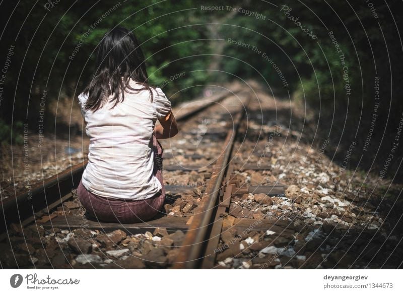 Sad young girl sitting lonely on rail track - a Royalty 