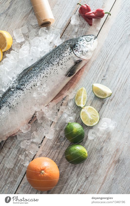 Raw salmon fish in ice and vegetables Seafood Vegetable Dinner Table Cook Paper Fresh Delicious Red White Salmon Lemon Baking paper knife wooden Tomato Broccoli