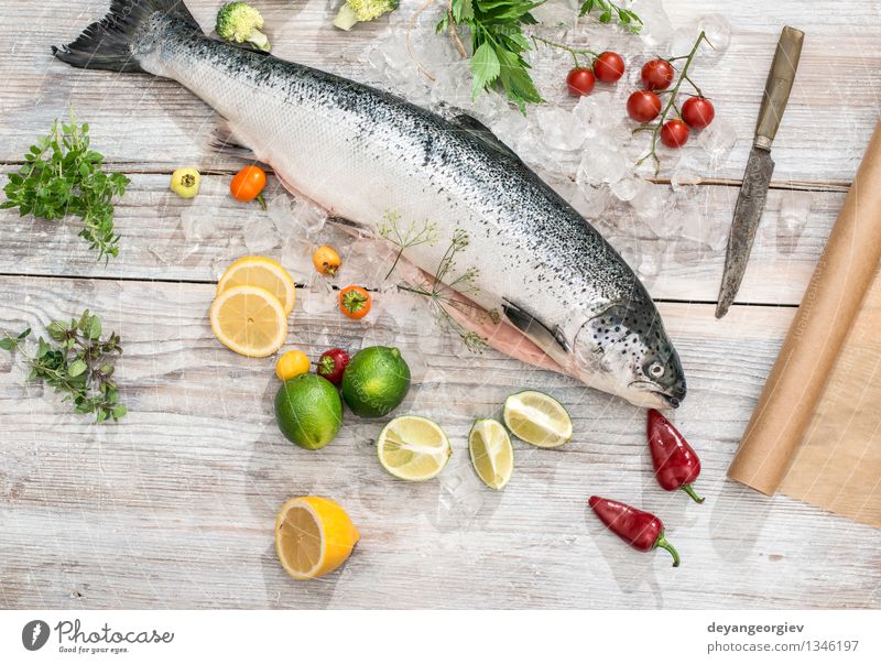 Raw salmon fish in ice and vegetables Seafood Vegetable Dinner Table Cook Paper Fresh Delicious Red White Salmon Lemon Baking paper knife wooden Tomato Broccoli