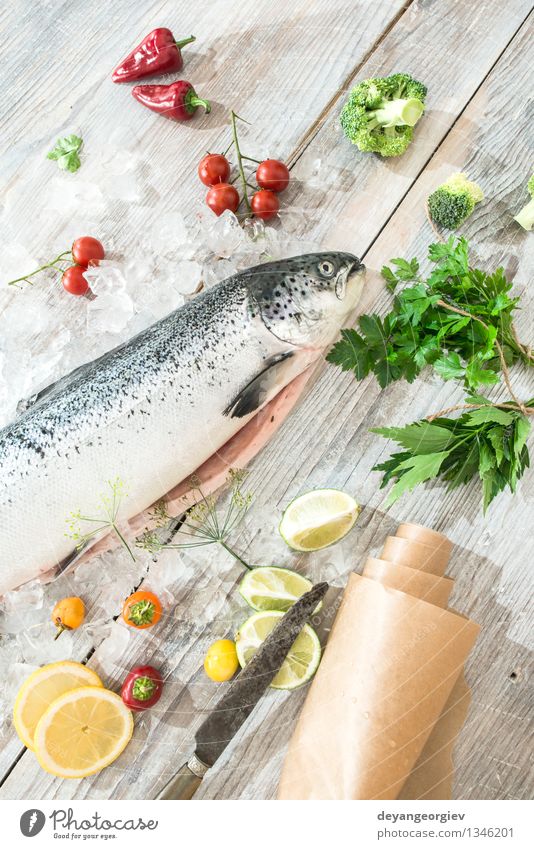 Raw salmon fish in ice Seafood Vegetable Dinner Table Cook Paper Fresh Delicious Red White Salmon Lemon Baking paper knife wooden Tomato Broccoli peppers