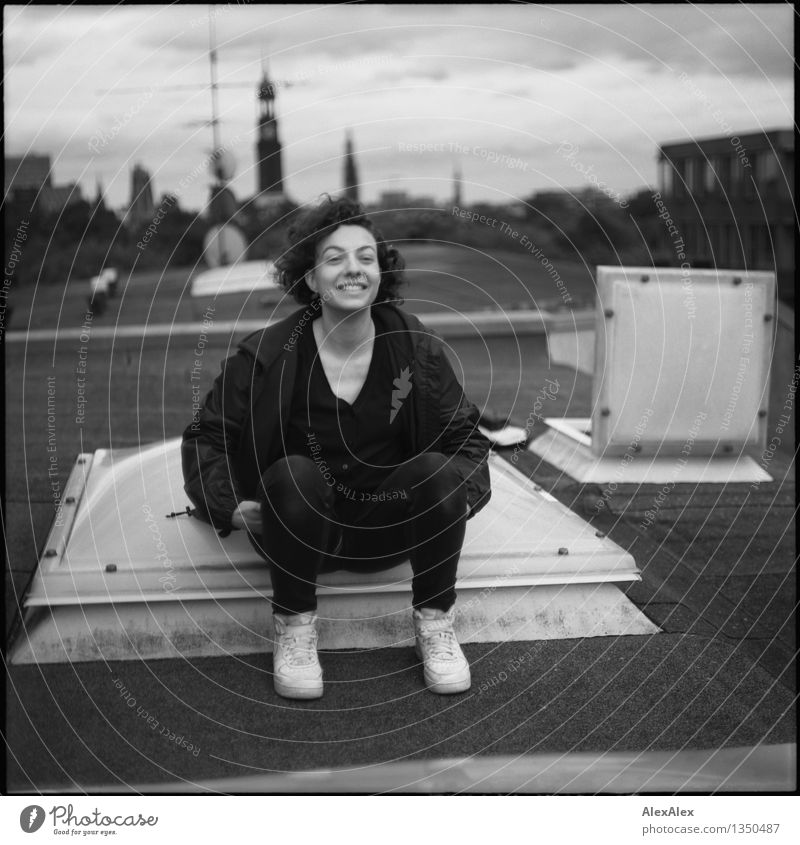uprising Young woman Youth (Young adults) 18 - 30 years Adults Town Skyline Roof St. Michael's Church Sneakers Brunette Curl Skylight Smiling Laughter Sit