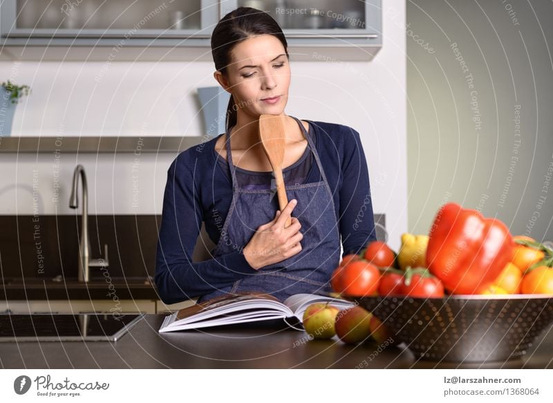 Woman Holding Ladle While Reading a cookbook Vegetable Fruit Nutrition Bowl Face Kitchen Gastronomy Adults 1 Human being 30 - 45 years Book Think Modern Natural