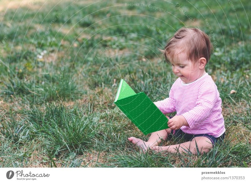 Little baby girl watching a book with pictures Lifestyle Joy Happy Beautiful Child Human being Baby Toddler Girl Infancy 1 0 - 12 months Book Grass Observe