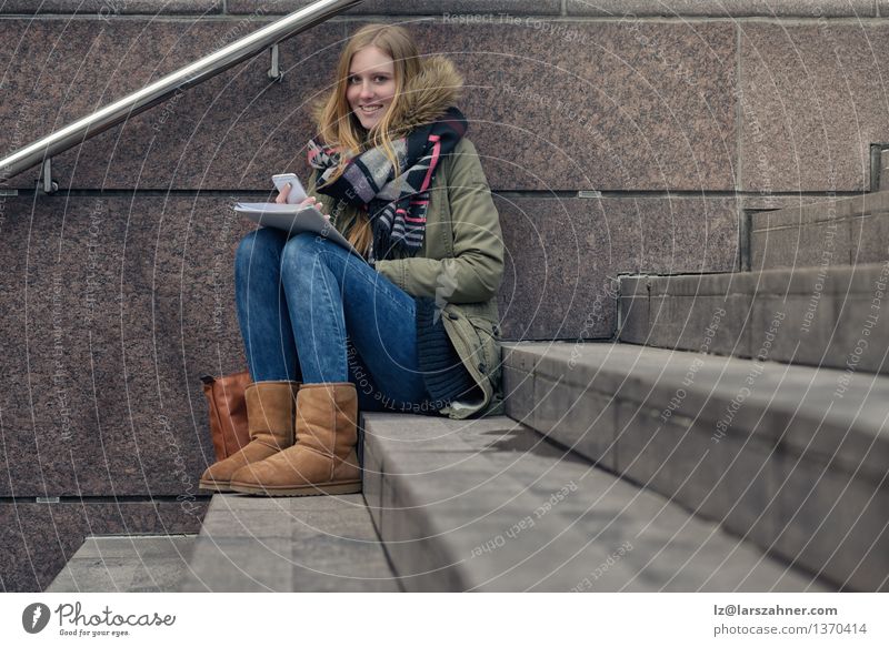 Attractive teenager sitting on steps in town Lifestyle Happy Face Reading Winter School Study Telephone PDA Girl Woman Adults 1 Human being 13 - 18 years