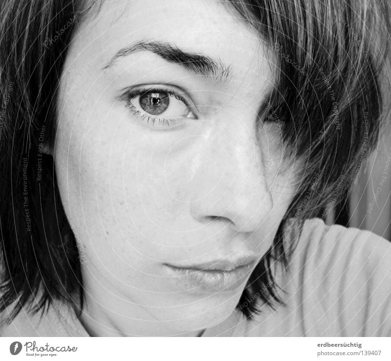 Portrait of a young woman with dark hair, bangs over one eye, the other looking intently into the camera Hair and hairstyles Skin Face Woman Adults Eyes Nose