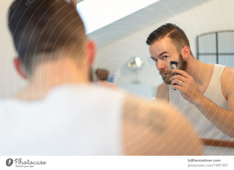 Young man shaving above his beard Face Mirror Bathroom Man Adults Beard Clean Precision appearance care Caucasian Cheek concentrating focusing getting ready