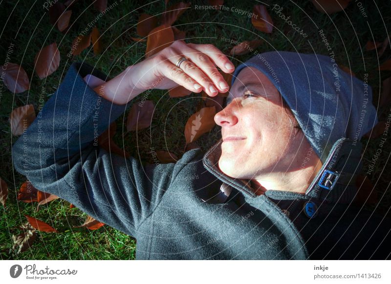 Woman with cap lies in autumn leaves Lifestyle Well-being Contentment Senses Relaxation Calm Leisure and hobbies Adults Face Hand 1 Human being 30 - 45 years