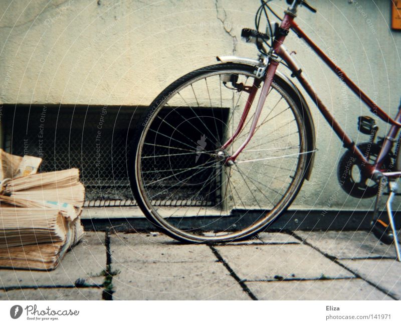 left Sidewalk Bicycle Newspaper Old Yellowed Tire Spokes Grating Wall (building) Flow House (Residential Structure) Parking Magazine Detail. cellar window wean