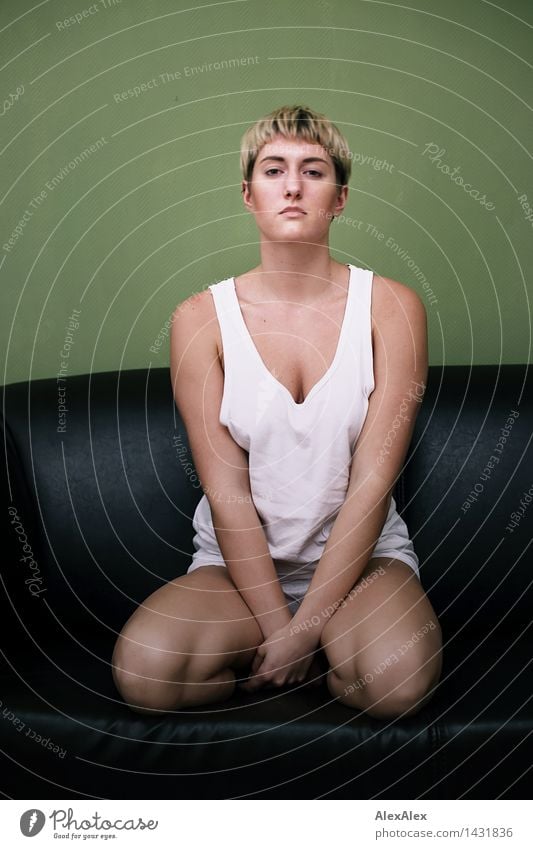 Young athletic slim woman kneels in underwear on dark couch in front of green wall Harmonious Relaxation Calm Young woman Youth (Young adults) Body