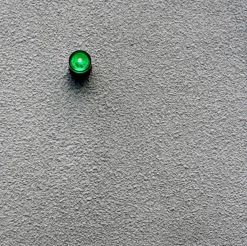 Small green alarm light... Alarm Alarm system Light Lamp Green Signal Wall (building) Plaster Gray Gloomy Exterior shot Minimalistic Warning signal