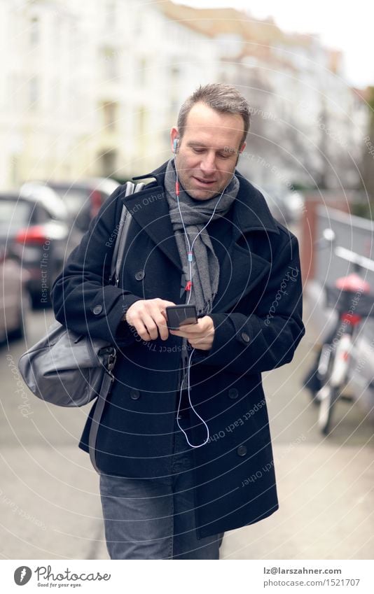 Attractive man in winter fashion checking his mobile Winter Business To talk Telephone Technology Masculine Man Adults 1 Human being 30 - 45 years Street