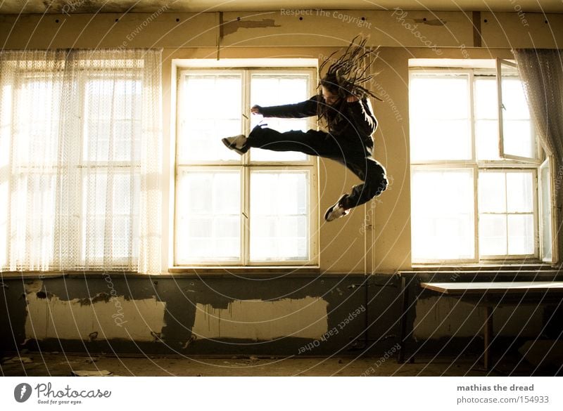 Dynamic young man with long hair lands on the roof of a big city - a  Royalty Free Stock Photo from Photocase