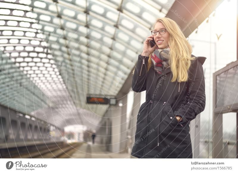 Blond woman with mobile phone at train station Happy Face Winter Telephone PDA Feminine Woman Adults 1 Human being 18 - 30 years Youth (Young adults) Transport