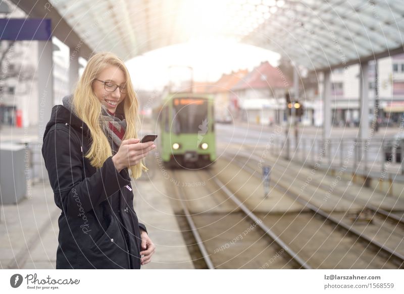 Young woman with mobile phone at train station Happy Vacation & Travel Winter Telephone Woman Adults 1 Human being 18 - 30 years Youth (Young adults) Transport