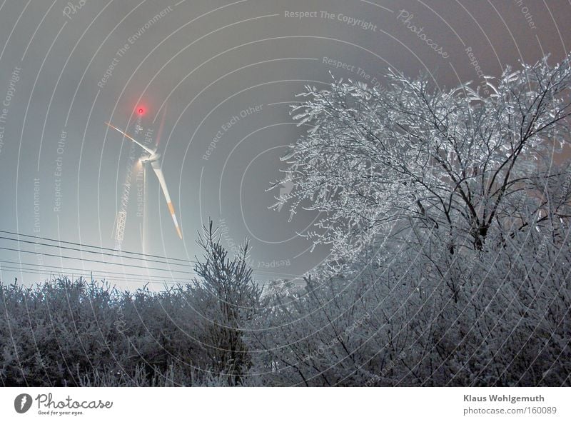 Wind turbine assembly at night and severe frost. A crane in the background and hoarfrost on tree and bush Winter Snow Lamp Work and employment Construction site