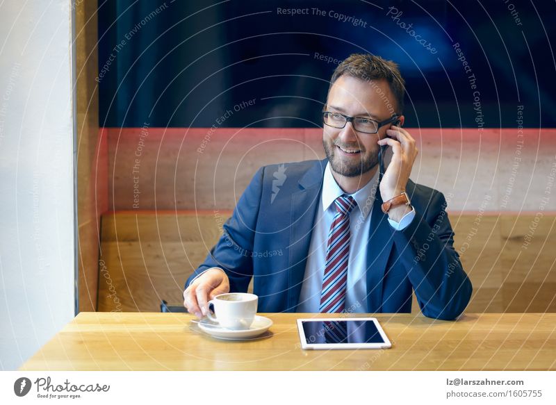 Handsome businessman with striped tie sits at table with coffee making phone call and using his tablet Coffee Work and employment Business Telephone Technology