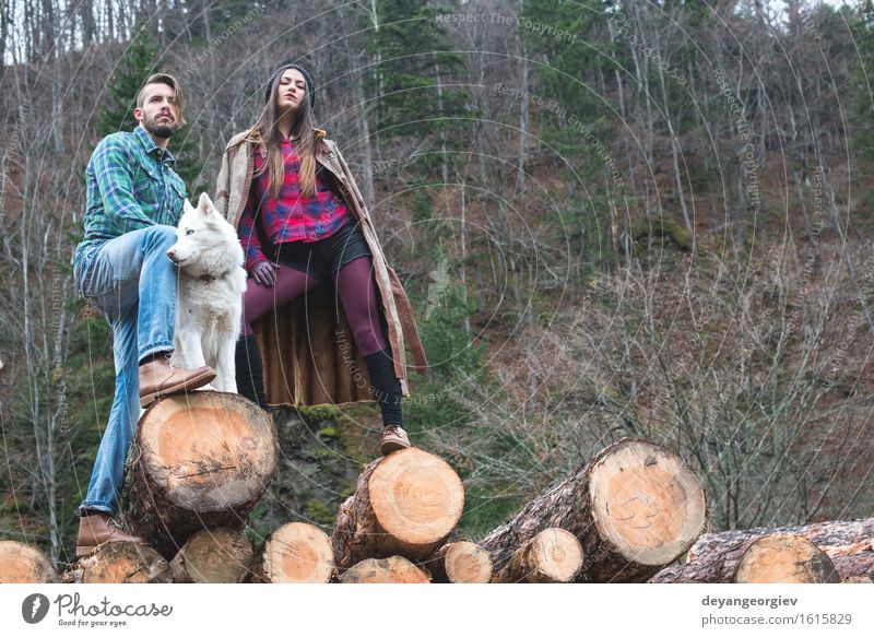 Young woman and men on wood logs in the forest Lifestyle Happy Leisure and hobbies Girl Woman Adults Man Couple Nature Tree Park Forest Fashion Footwear Dog