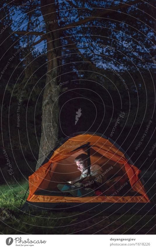 Man watching his smartphone in a tent Lifestyle Happy Vacation & Travel Adventure Camping Summer Hiking Telephone PDA Human being Adults Friendship Forest Dark