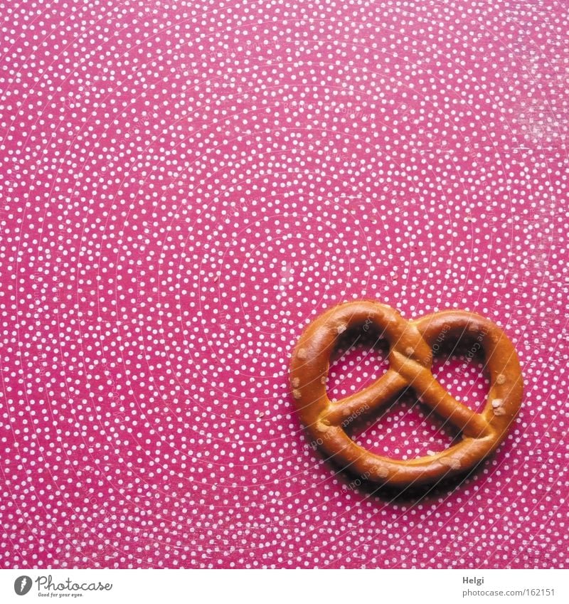 a salt pretzel lies on a background with red and white dots Pretzel Baked goods Nutrition Nibbles Salty Feasts & Celebrations Delicious Red White Brown Point