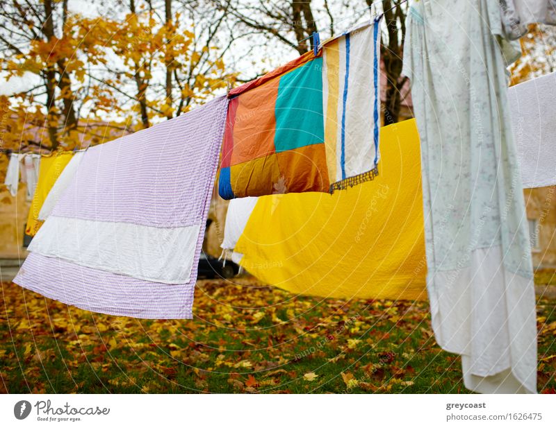 Bright colorful linen dried out in the yard. Garden Landscape Autumn Park Cloth Blue Yellow Red Colour Backyard background Consistency dry Material cell cellule