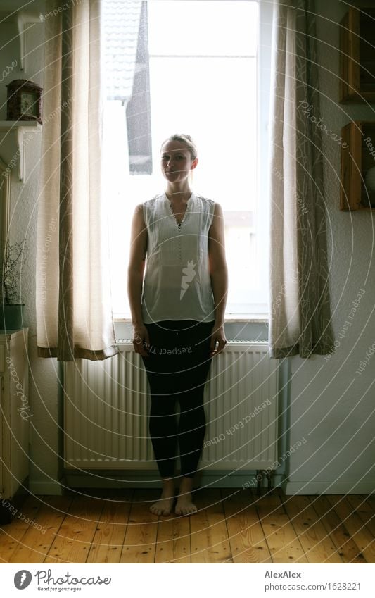 outside it is dark - young, sporty woman stands barefoot in front of a window in the room - backlight shot Heating Floorboards Window Curtain Young woman