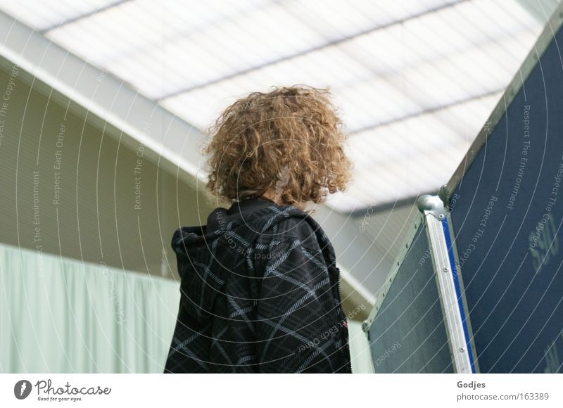 Person with curly hair looks over wall, face turned away Leisure and hobbies Event Sporting Complex Education Student Human being Masculine Youth (Young adults)
