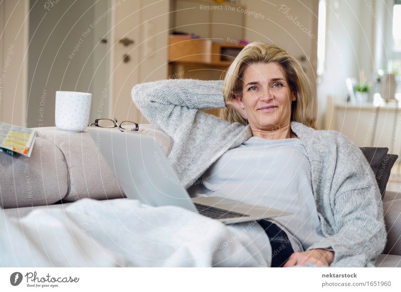 Blonde woman working from living room Lifestyle Joy Contentment Relaxation Leisure and hobbies Vacation & Travel Sofa Computer Notebook Internet Woman Adults