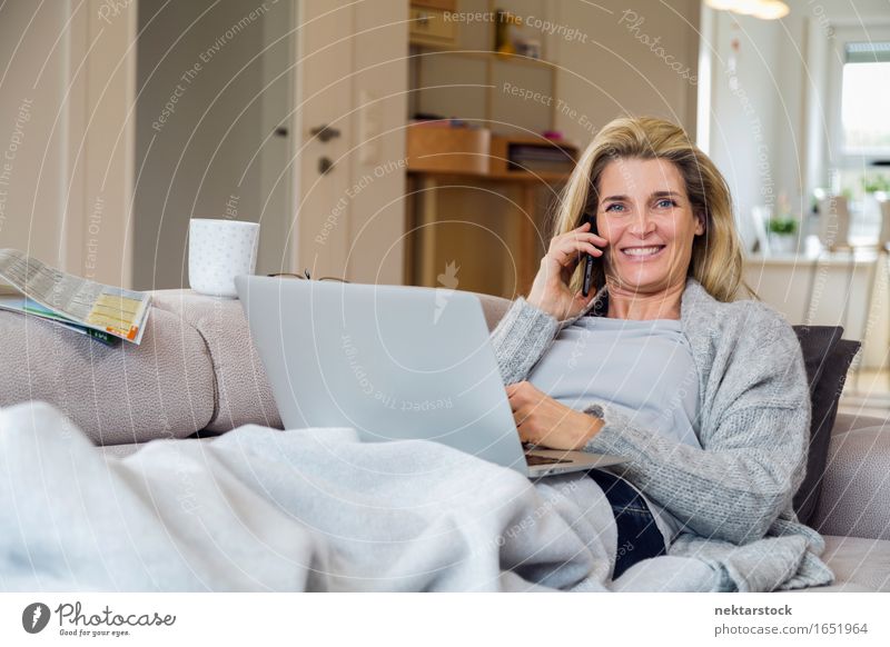 Blonde woman working from living room Lifestyle Happy Relaxation Leisure and hobbies Vacation & Travel Sofa To talk Telephone Computer Notebook Internet Woman
