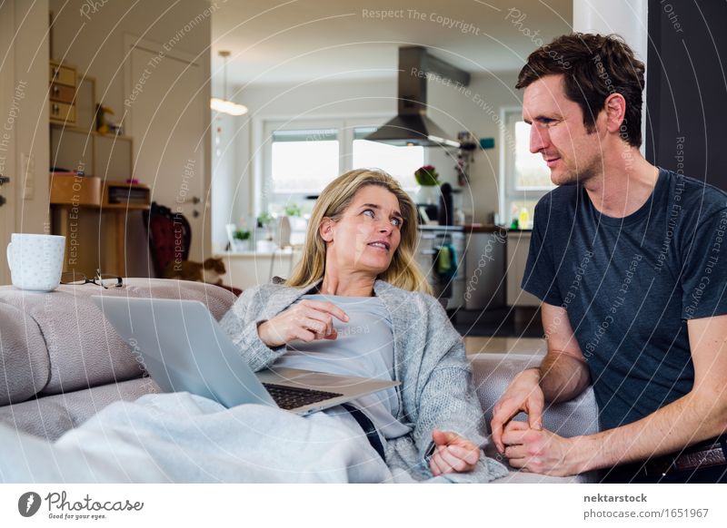Couple at home on sofa looking at laptop Calm Sofa Living room Computer Notebook Internet Woman Adults Man To talk Lie (Untruth) Home blanket Couch Cozy Online