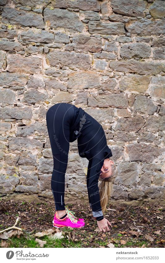 Woman stretching her body in front of ancient wall in park Lifestyle Body Wellness Sports Human being Adults Park Stone Touch Fitness Athletic Mobility Practice